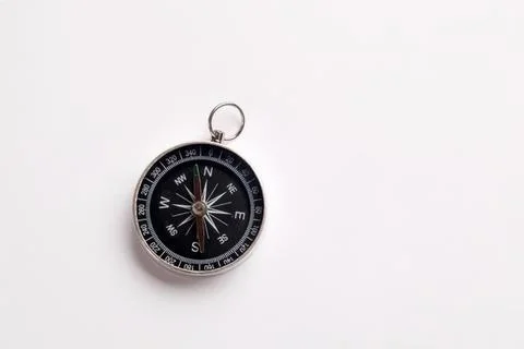 Small black compass with silver ring on white background Stock Photos