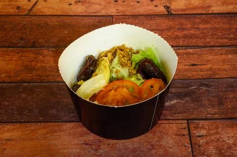 A small black container with a salad inside Stock Photos