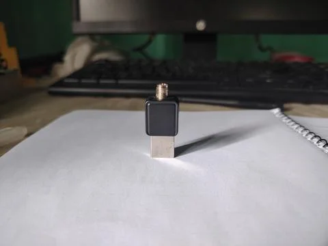 Small black electronic device standing on white paper desk next to spiral n.. 스톡 사진