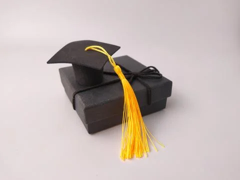 A small black graduation cap with a long yellow tassel sits a top a tied bl.. Stock Photos