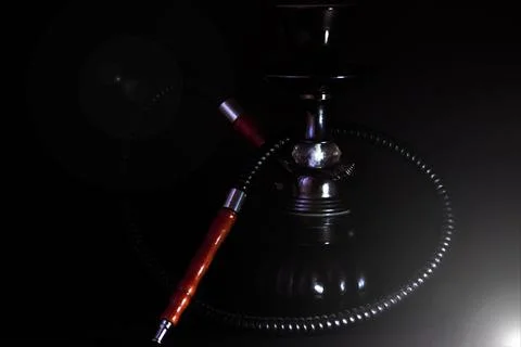 Small black hookah on a black background with a lens flare. Stock Photos