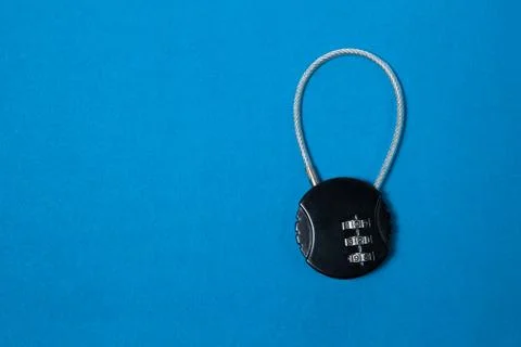 Small black iron cipher lock with a coded set on blue background 스톡 사진