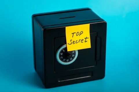 Small black safe with combination lock and "top secret" note on blue backgrou Stock Photos