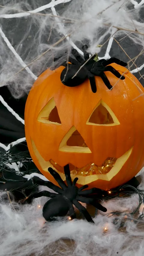 A small black spider crawls on a pumpkin with a white web with flashing lig.. Stock Footage 315983052
