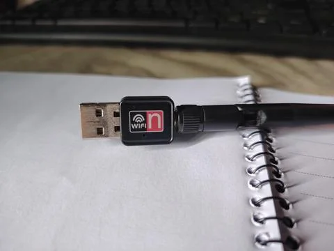A small black wireless USB adapter with a red and white n symbol is positio.. 스톡 사진