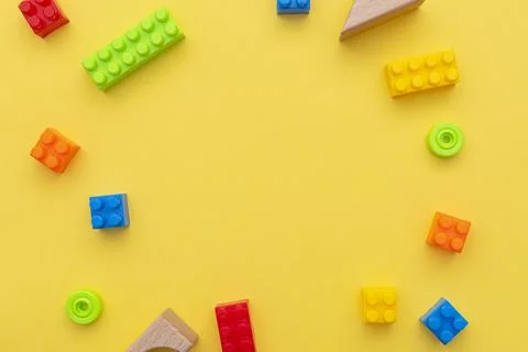 Small blocks of plastic constructor on yellow background, flat lay, top view Stock Photos