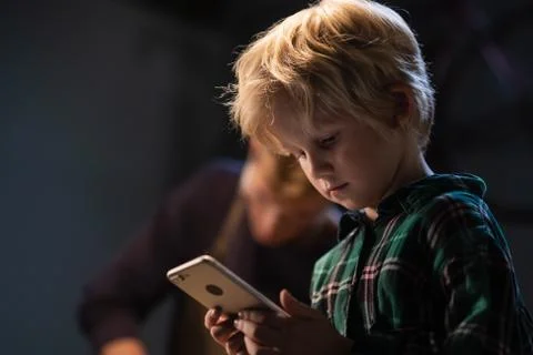 A small blond boy during a break in the labor lesson took a smartphone and Stock Photos