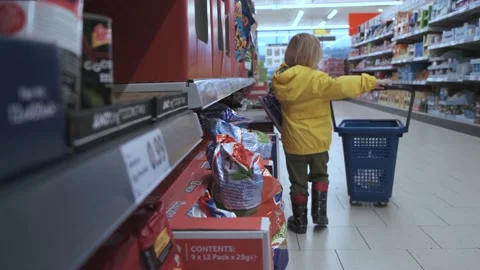 A small blond child himself carries a plastic basket in a supermarket, chooses a Stock Footage 231144698