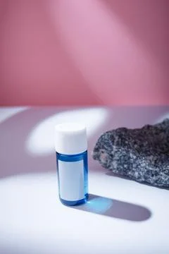 Small blue bottle with blank label, no brand mockup on white table Stock Photos