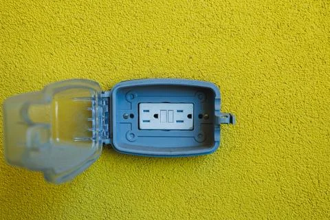 A small blue case is open on a bright yellow surface, showing a white devic.. Stock Photos