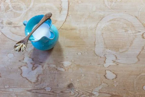 Small blue ceramic pitcher of oat milk with wooden spoon balanced across Stock Photos
