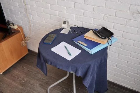 Small blue cloth covered table with papers, books, glasses, and digital clo.. Stock Photos