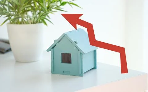 A small blue house is on a table with a red arrow pointing down Stock Photos