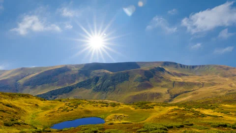 Small blue lake in mountain under a cloudy sky with sparkle sun Stock Footage 320191127