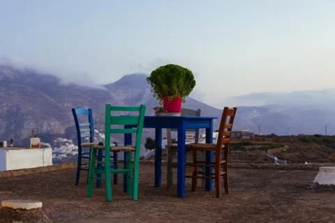 A small blue table with four multicolored chairs on the terrace at sunset Stock Photos