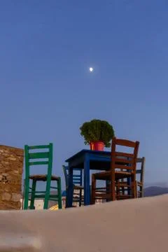A small blue table with four multicolored chairs on the terrace at sunset Stock Photos