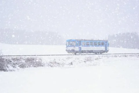 Small blue train in the winter landscape within a blizzard Фото
