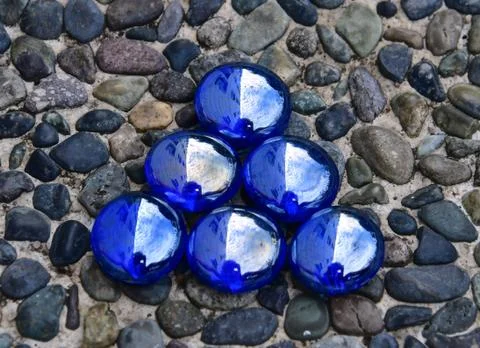 Small blue triangle on pebblestone background Stock Photos