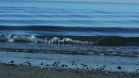 Small blue waves gently rolling in and breaking on to beach Stock Footage 249836966