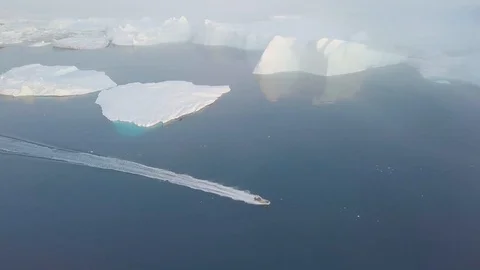 A small boat among icebergs in Disko Bay glacier during midnight sun Ilulissat. Stock Footage 128591753