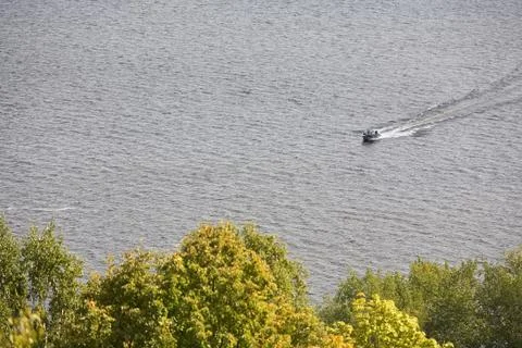 A small boat floating on the river on the background of trees. Stock Photos