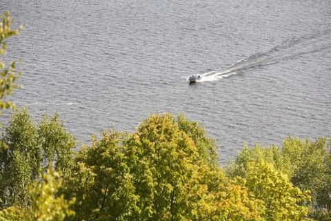 A small boat floating on the river on the background of trees. Stock Photos