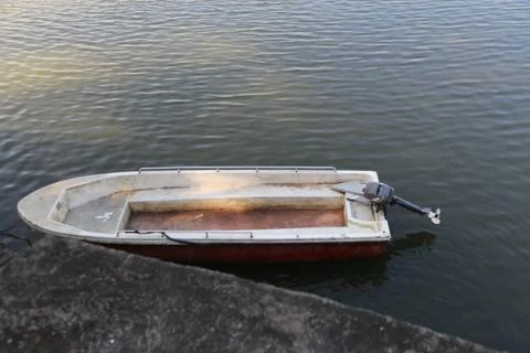 A small boat is floating on the water, with an engine at one end and no sea.. 스톡 사진