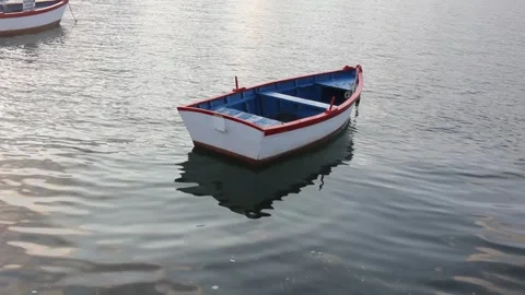 A small boat gently floating on the water at sunset Stock Footage 311429527