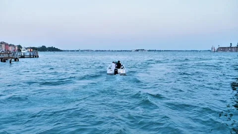 A small boat glides across the vast Venetian lagoon at dus Stock-Footage 313844945