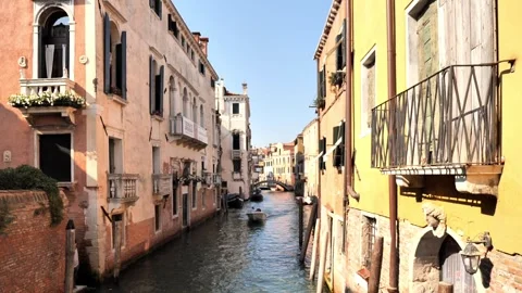 A small boat glides through a sunlit Venetian canal flanked by pastel buildings. Stock-Footage 314622876