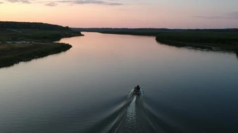 Small boat going down river at sunset 2 Stock Footage 254980130