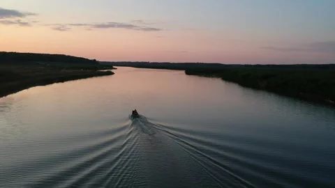 Small boat going down river during sunset Stock Footage 254980131