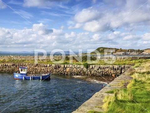 A small boat moored along the shore of Strangford Lough Stock Photos