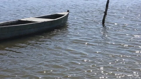 Small boat moored to a rustic wooden pole by rope Stock Footage 318594546