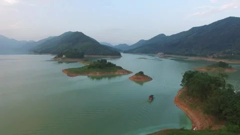 A small boat navigates a lake surrounded by mountains and islands Stock Footage 312303482
