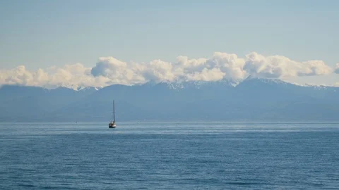 Small boat out on large ocean with giant mountains in the far distance Vídeos de archivo 122232692