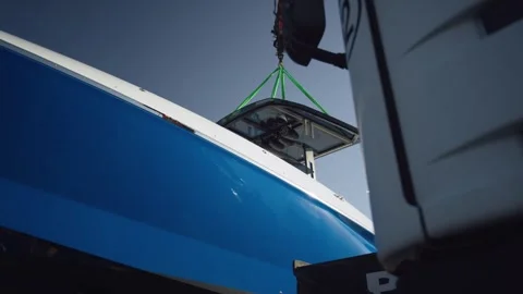 Small Boat Part Rigged on Green Straps beside Blue Yacht Bow, Low Angle View Stock Footage 340332997