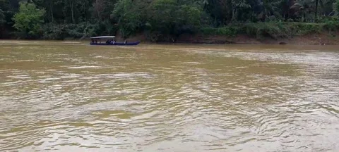 Small boat passing on a big river in a village Stock Footage 296304155