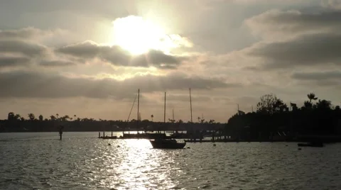 Small boat passing through perfectly serene shot of sun setting behind clouds Video stock 67467188