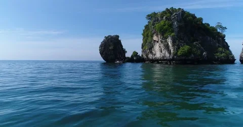 Small boat passing twin jungle topped limestone stacks 動画素材 71298896