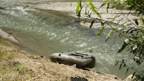 A small boat is peacefully sitting on the sandy shore of a river Video stock 313935790
