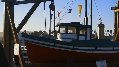A small boat rests below flags on Santa Cruz Wharf, California Stock Footage 95609465