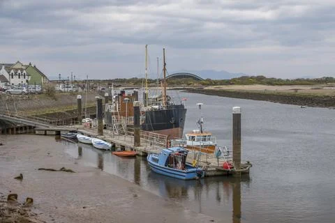 Small boat rests at harbor dock beside larger vessel Stock Photos