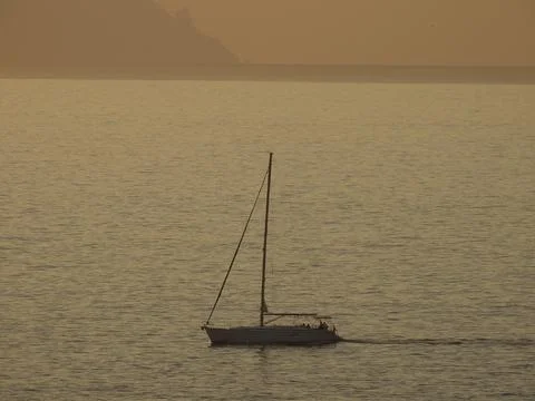 Small boat sailing as the sun sets Stock Photos
