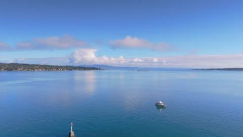 Small boat sails across the calm blue water on a sunny day aerial view Stock Footage 289242557