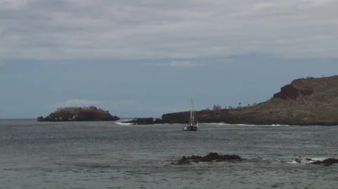 A small boat separates itself from a larger ship near the shore of an island in Stock Footage 39479527