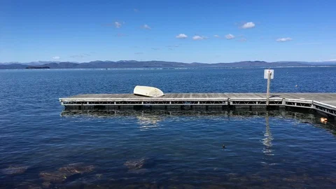Small Boat Sits on Dock Overlooking Picturesque Lake and Mountains Stock Footage 89301363