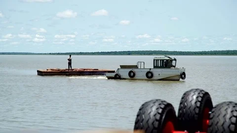 A small boat towing a floating platform on a lake. Video stock 71085484