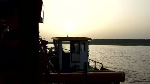 A small boat towing a large floating platform during sunset. Stock Footage 71179836