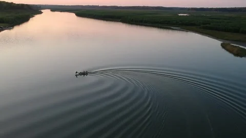 Small boat turning around in a river at sunset Stock Footage 254980134